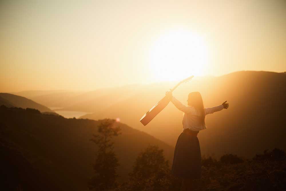 en tjej med goitarr i solnedgången.